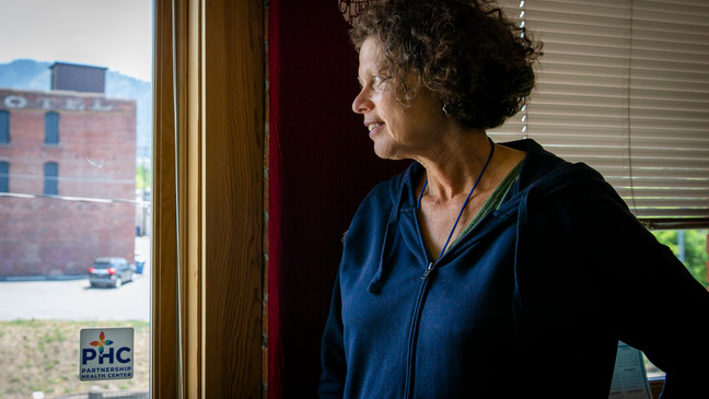 Helen Maas, a senior community health specialist for Partnership Health Center, looks out the window of her office in Missoula, Montana. (Erica Zurek for KFF Health News)